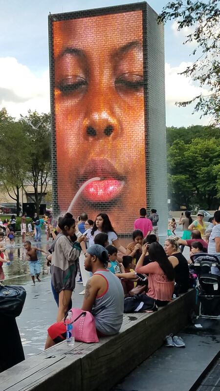 An image of a young human's face seems to spit a stream of water at the Millennium Park Splashpad, North Michigan Avenue, Chicago.