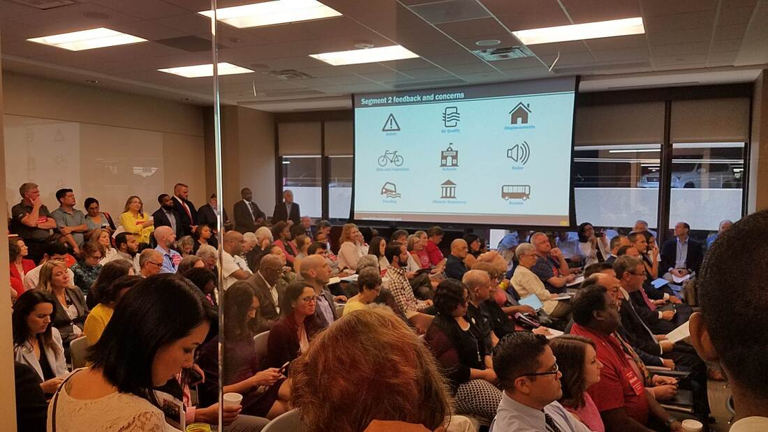 Several hundred people attend the Houston-Galveston Area Council's meeting on the proposed North Houston Highway Improvement Plan. A screen shows the list of concerns such as safety and noise pollution.