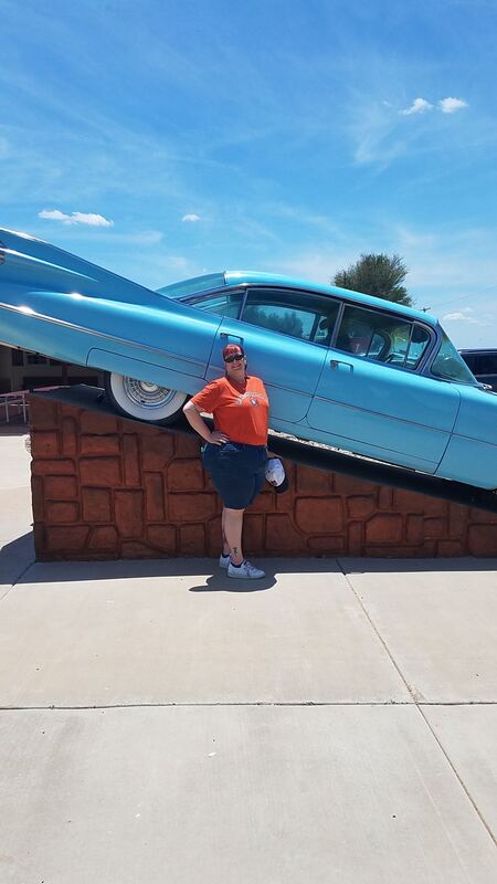 Kayleen standing with a blue 1957 Cadillac Sedan de Ville by the Cadillac Ranch souvenir shop.