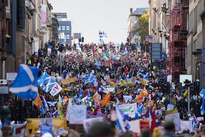 A throng of environmental activists floods into the streets of Glasgow, including some Scottish Independence advocates carrying Scottish flags.