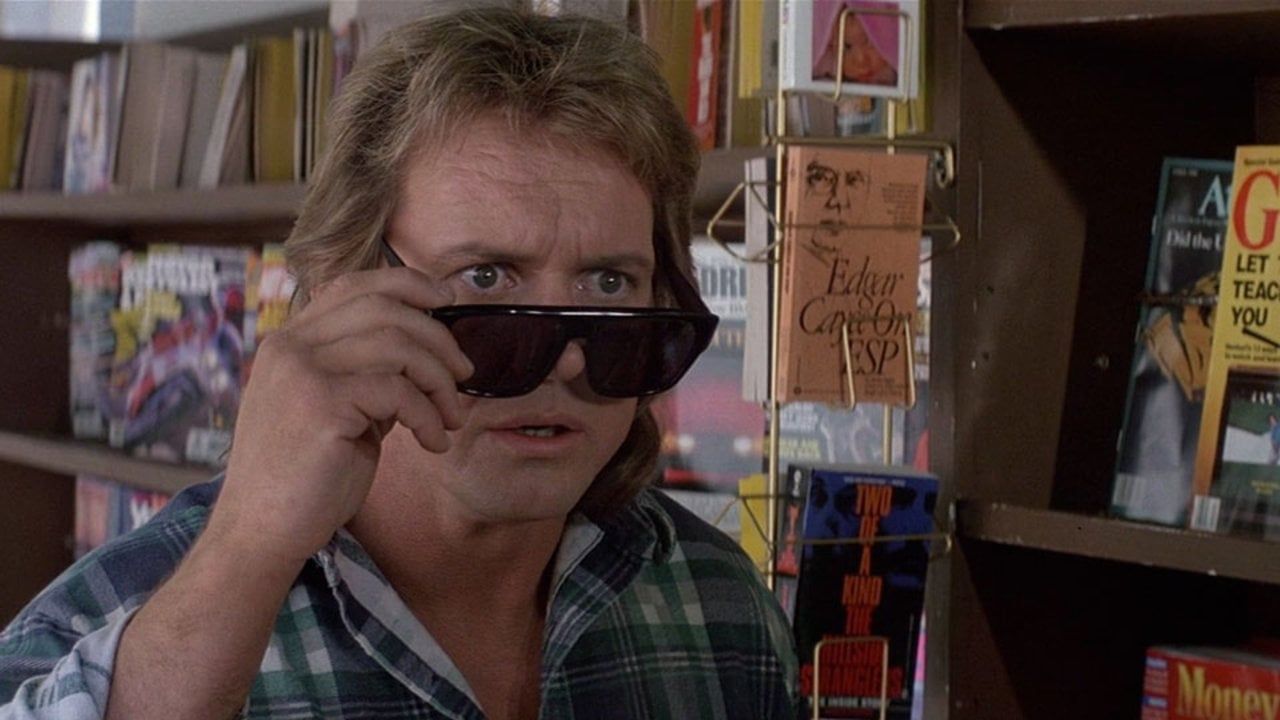 Still of Roddy Piper trying on a pair of narrative-piercing sunglasses in a bookstore, from  